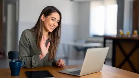 Medewerker werkt thuis achter een laptop met videovergadering op het scherm